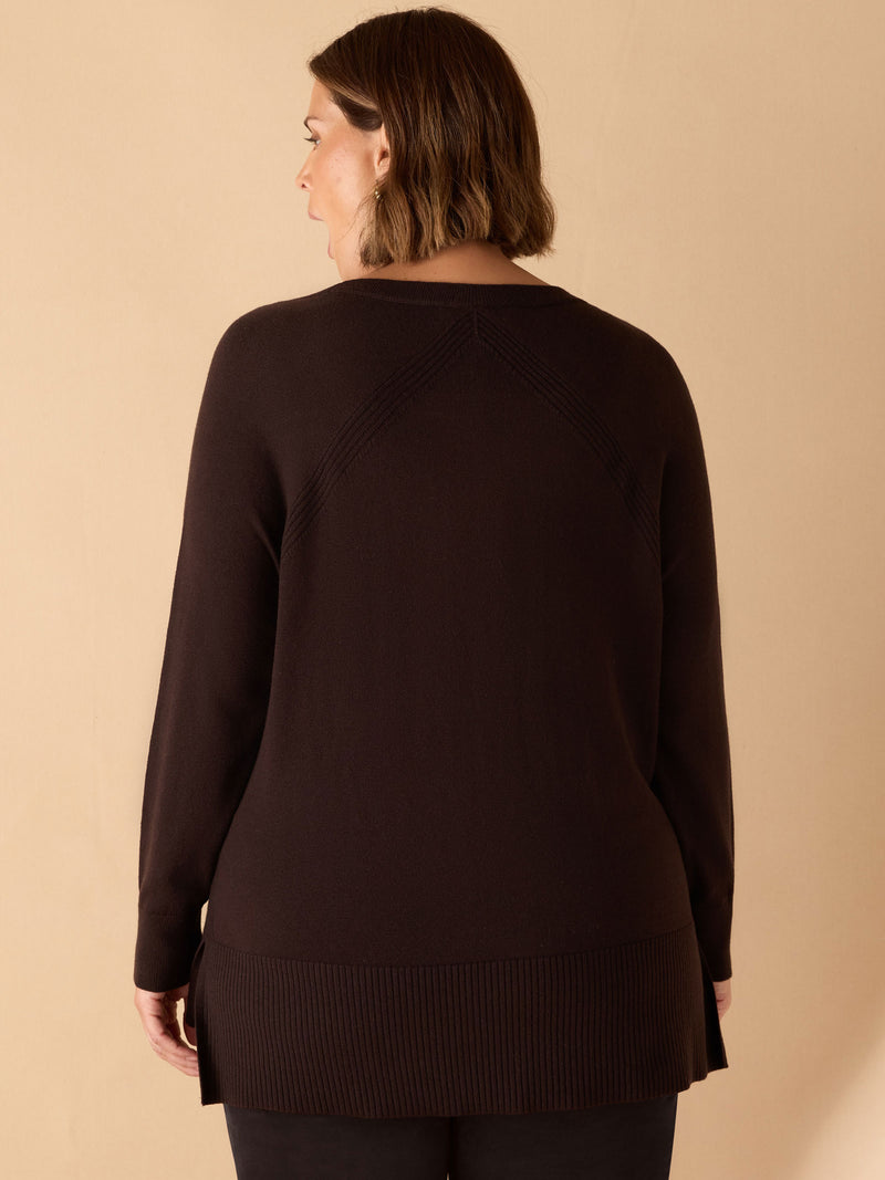 Woman wearing a dark brown sweater against a beige background