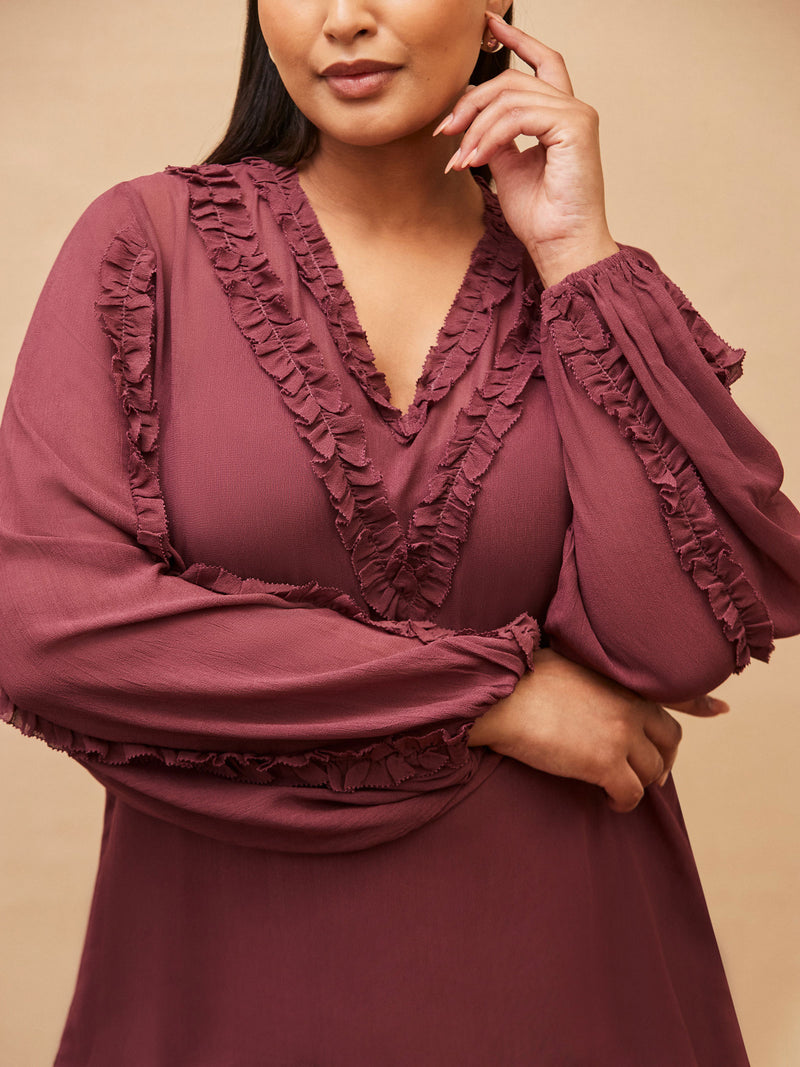 Mauve dress with ruffled details on a beige background