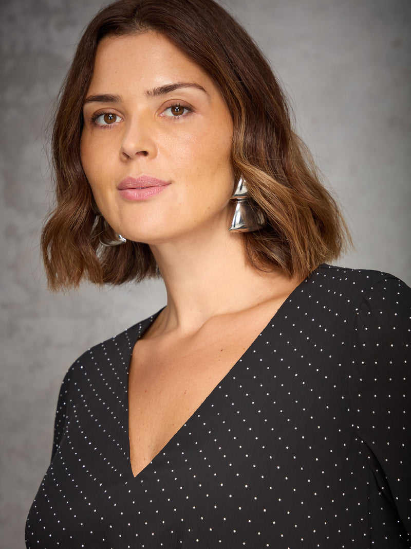 Woman wearing a black sparkle dress against a gray background