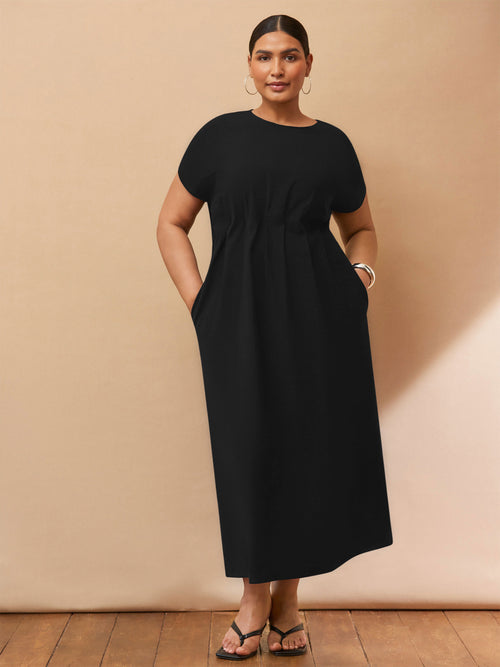 Woman wearing a black dress against a beige background