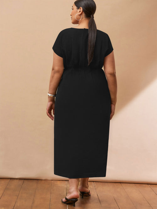 Woman wearing a black dress against a beige wall