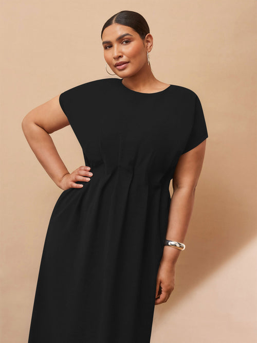 Woman wearing a black dress against a beige background