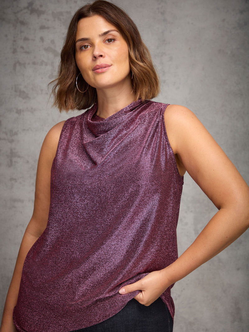 Woman wearing a sparkly purple sleeveless top against a gray background