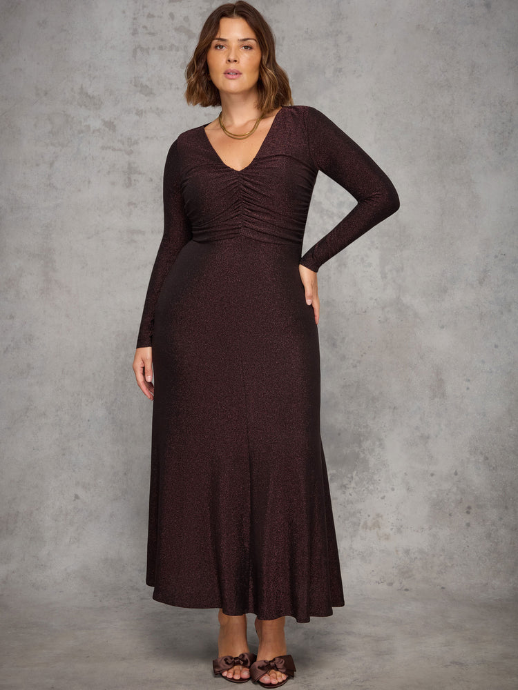 Woman wearing a long brown dress against a gray background
