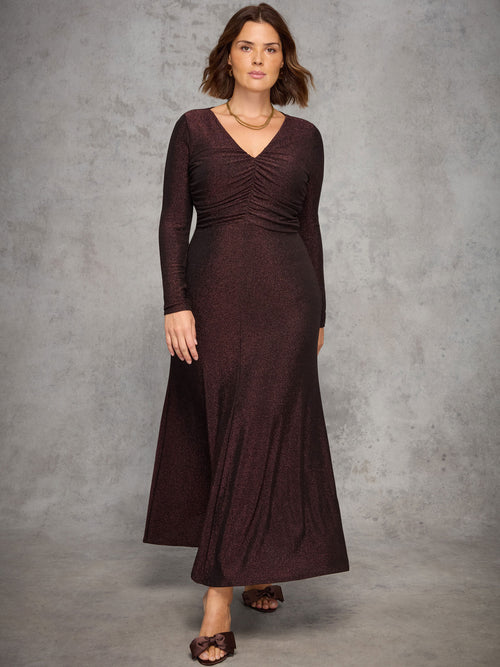 Woman wearing a long burgundy dress against a gray background