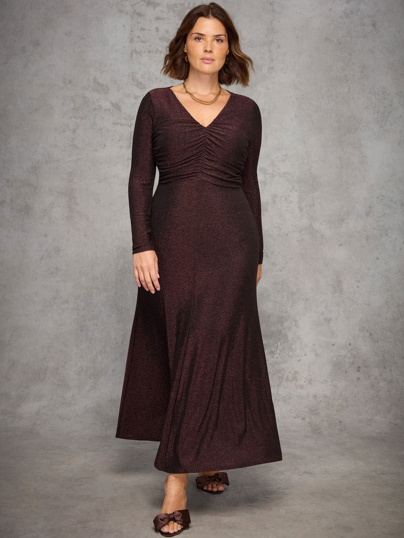Woman wearing a long burgundy dress against a gray background