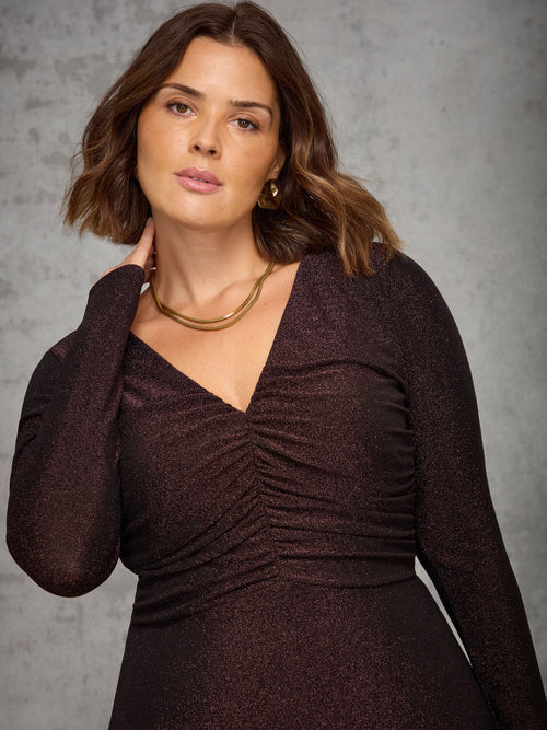 Woman wearing a dark brown dress against a gray background