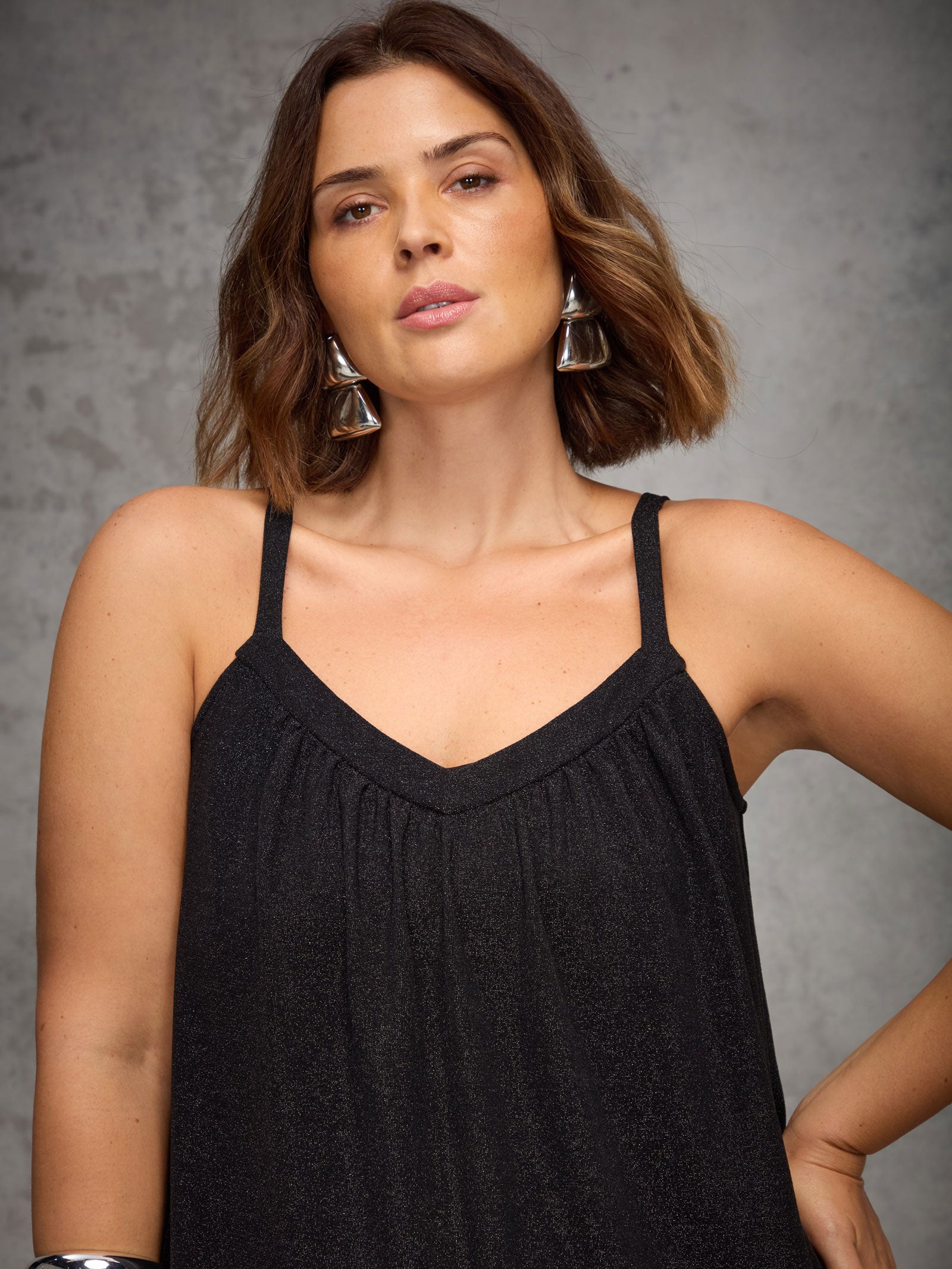 Woman wearing a black sleeveless top against a gray background