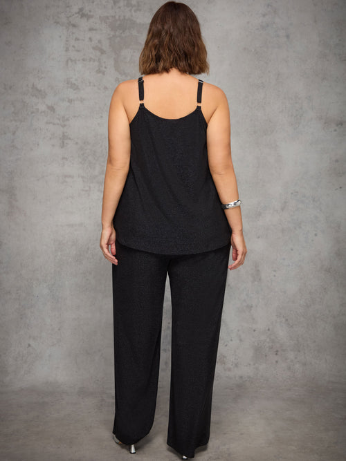 Person wearing a black sleeveless top and black pants against a gray background