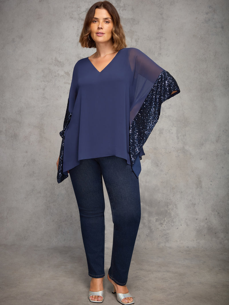 Woman wearing a navy blue top and pants with a matching shawl against a gray background