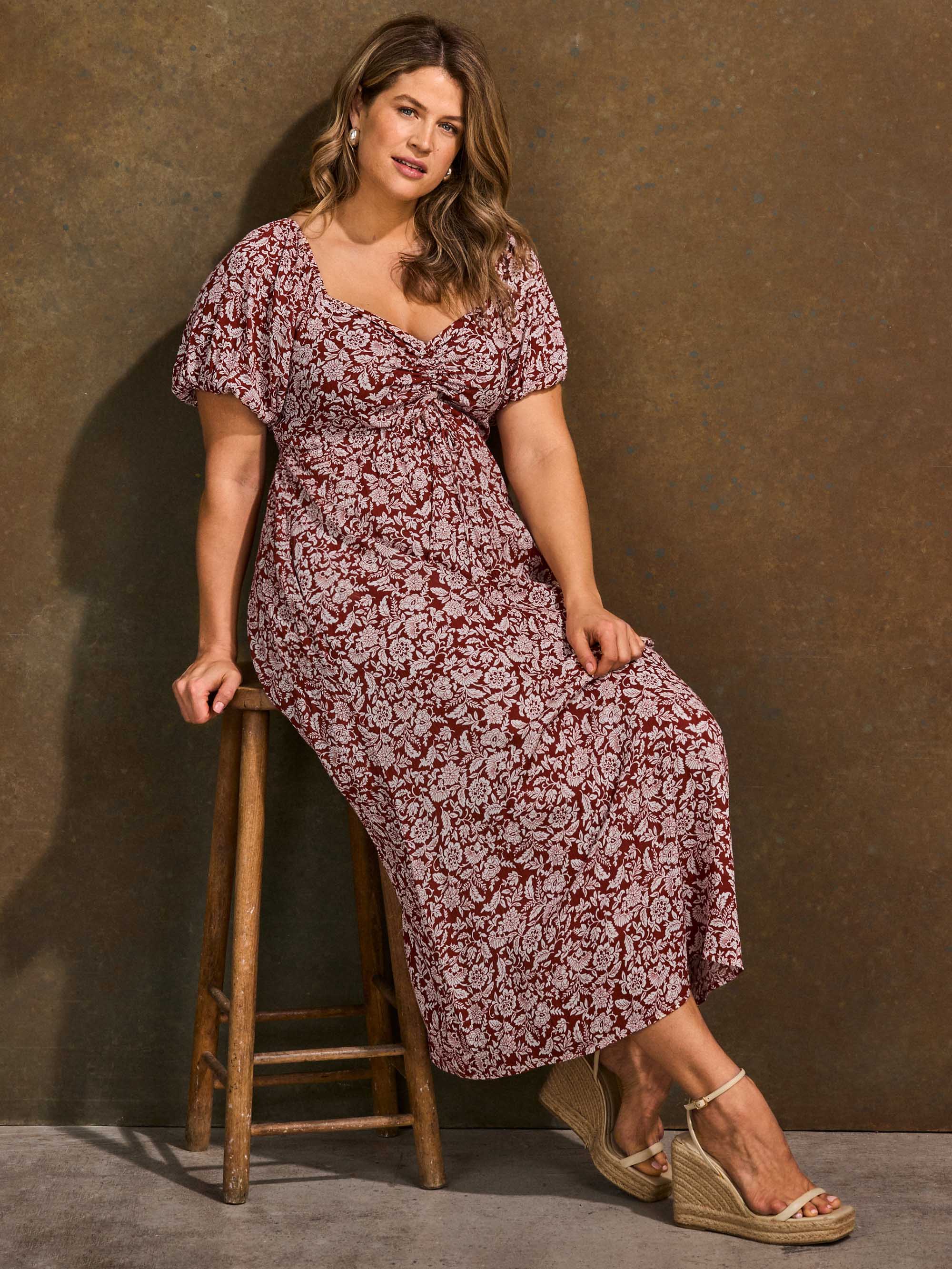 Rust floral midaxi dress styled sitting on stool