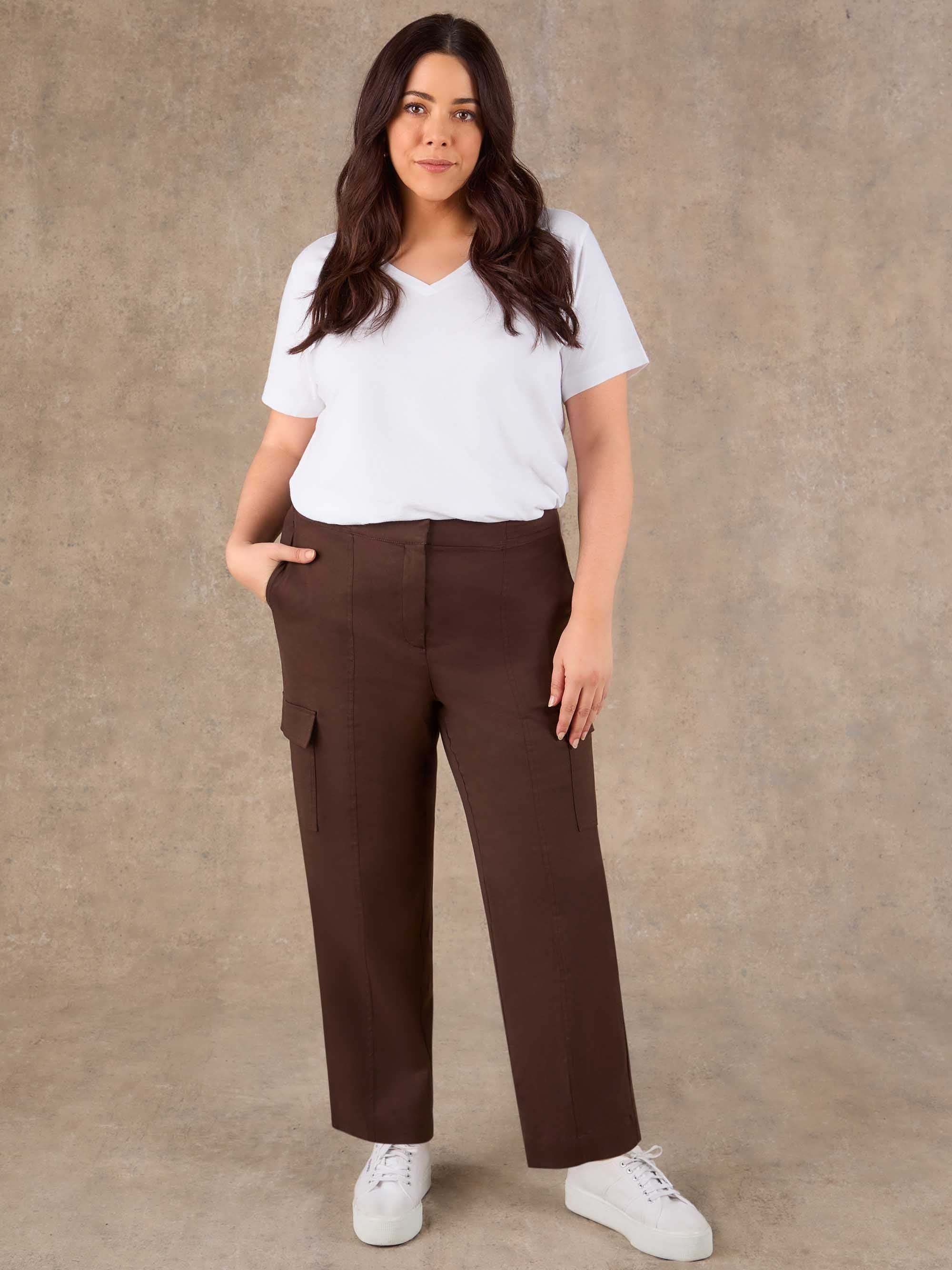 Woman wearing a white t-shirt and brown cargo pants against a beige background