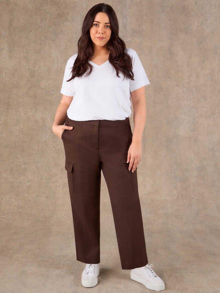 Woman wearing a white t-shirt and brown cargo pants against a beige background