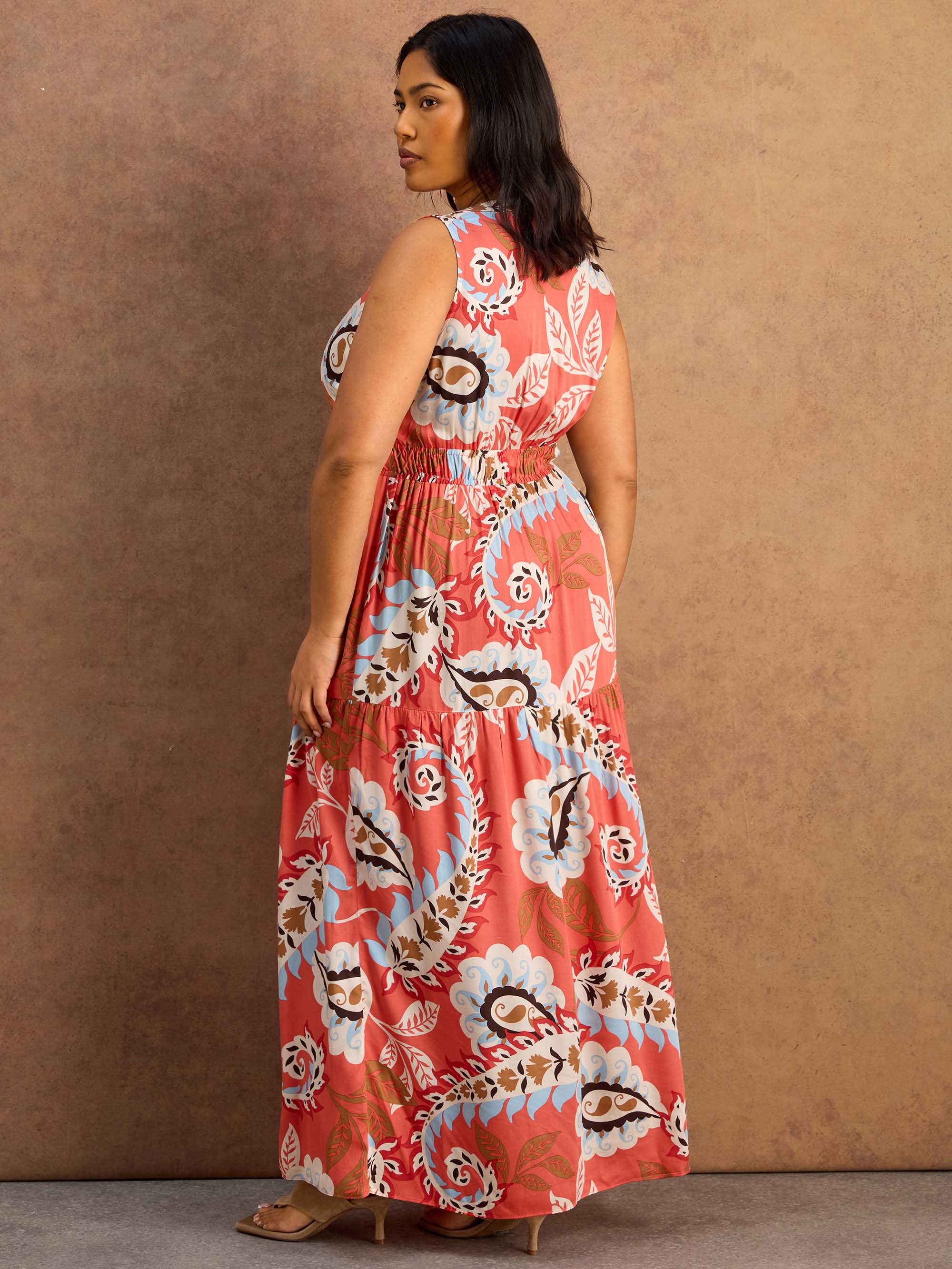 Woman wearing a floral maxi dress against a brown background