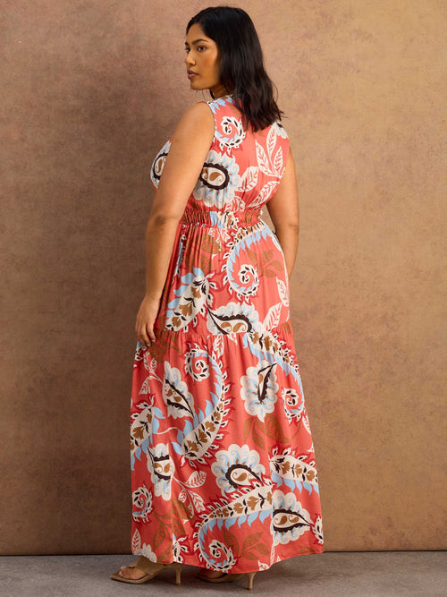 Woman wearing a floral maxi dress against a brown background