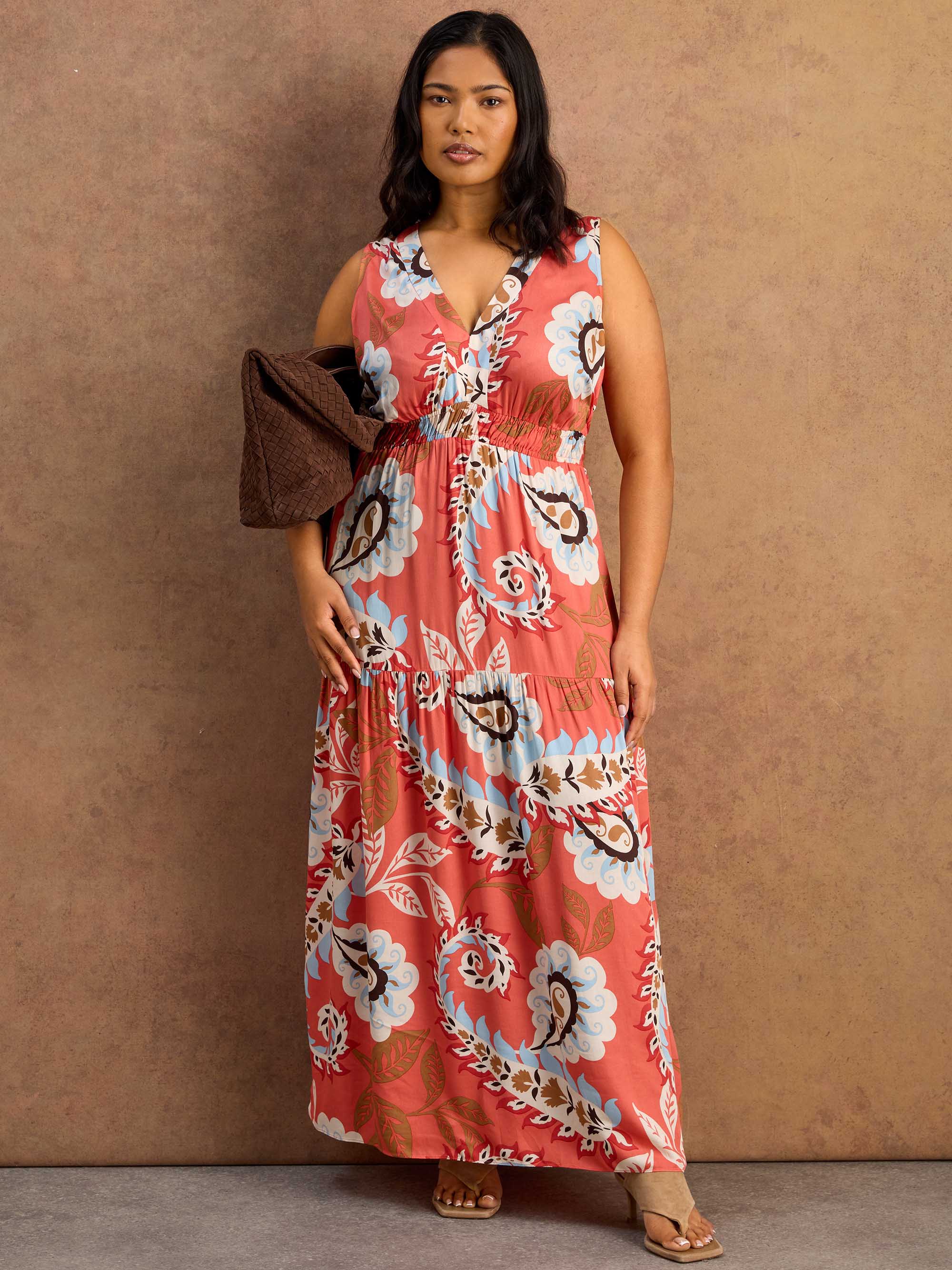 Woman wearing a floral maxi dress against a brown background