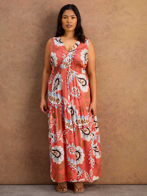 Woman wearing a floral maxi dress against a brown background