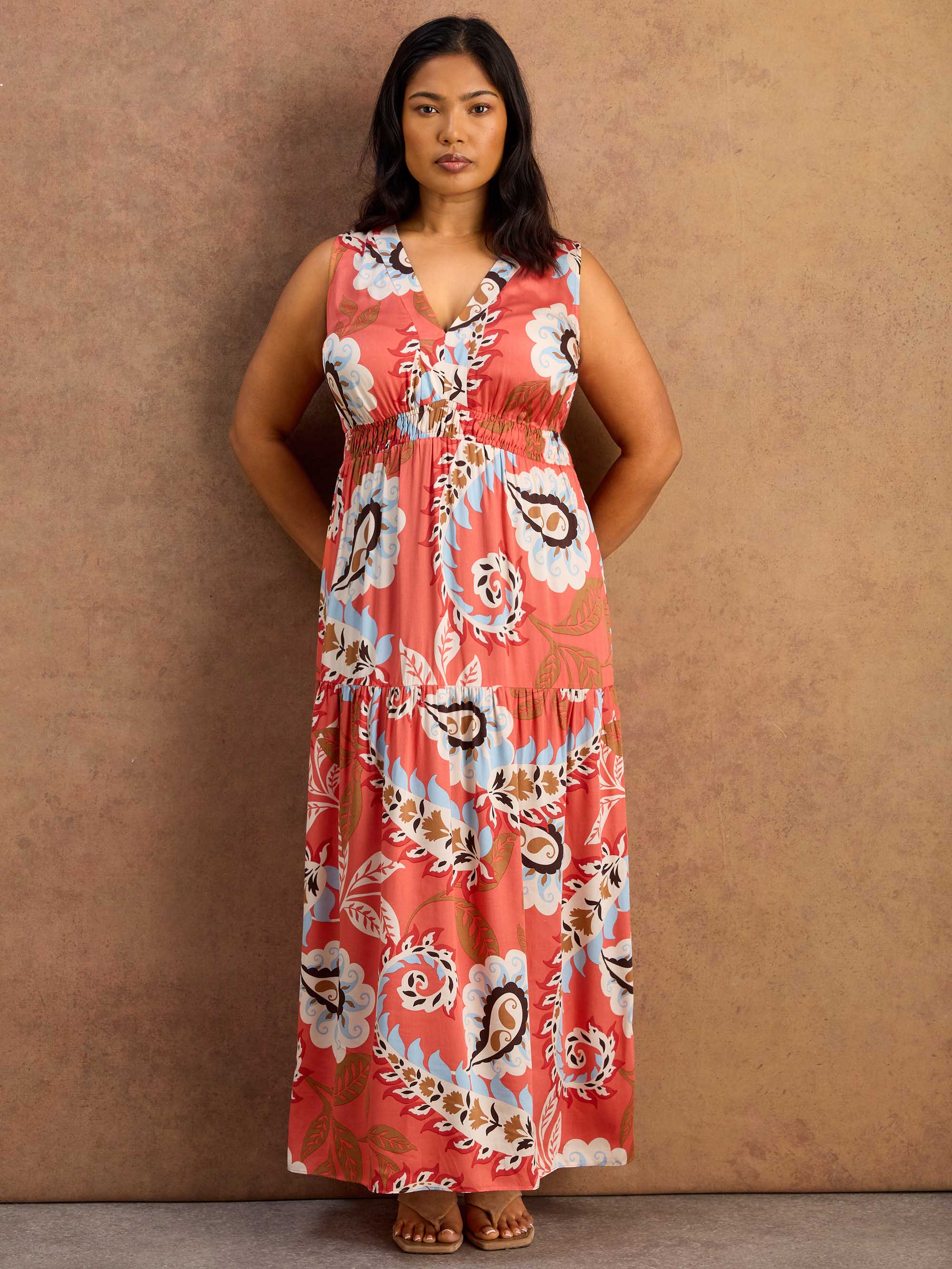 Woman wearing a red floral maxi dress against a brown background