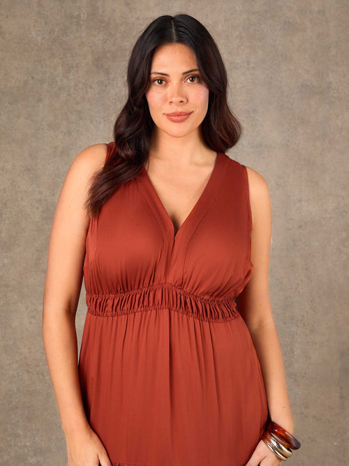 Woman wearing a rust-colored dress against a neutral background