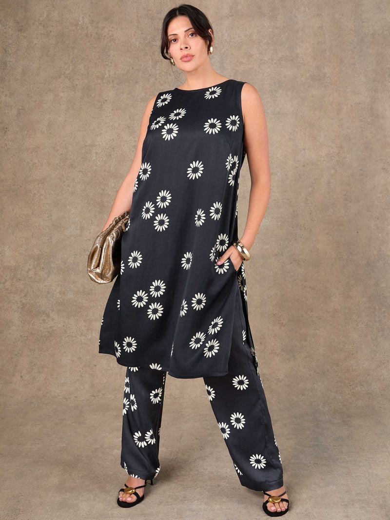 Woman wearing a black outfit with white floral patterns against a brown background