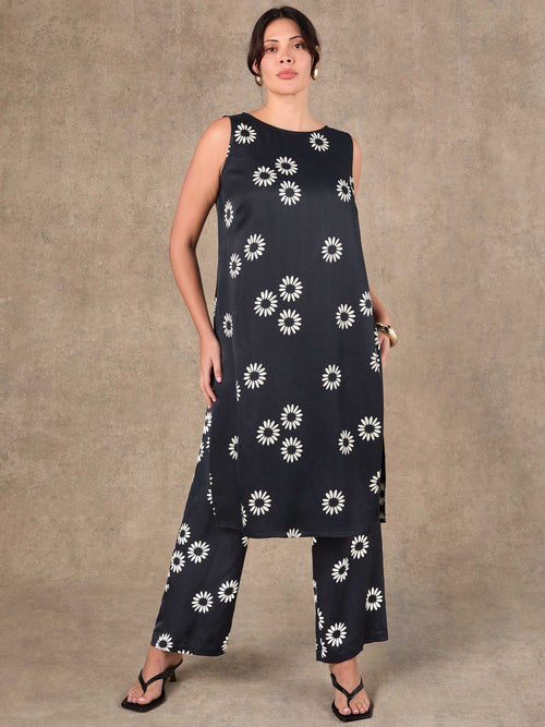 Woman wearing a navy blue dress with white floral patterns on a beige background