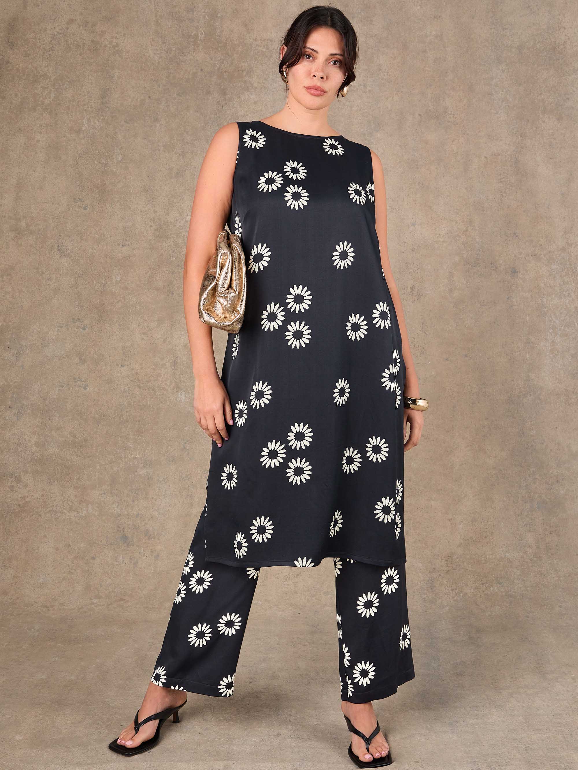 Woman wearing a black dress with white floral patterns against a brown background