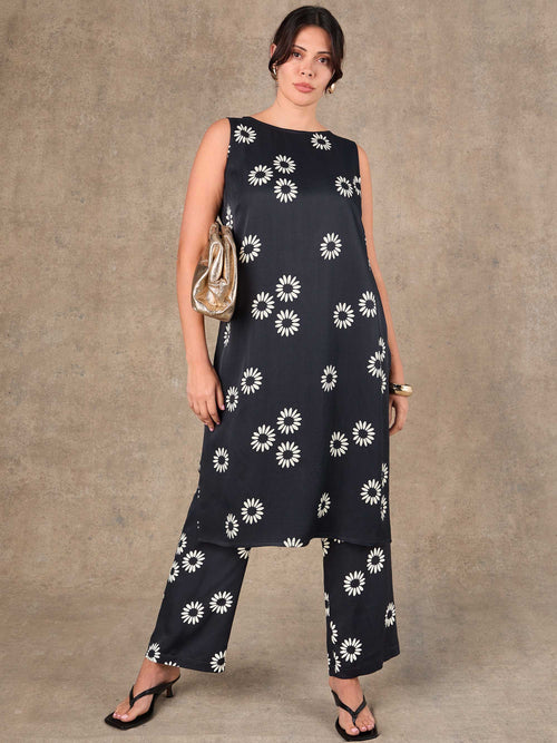 Woman wearing a black dress with white floral patterns against a brown background