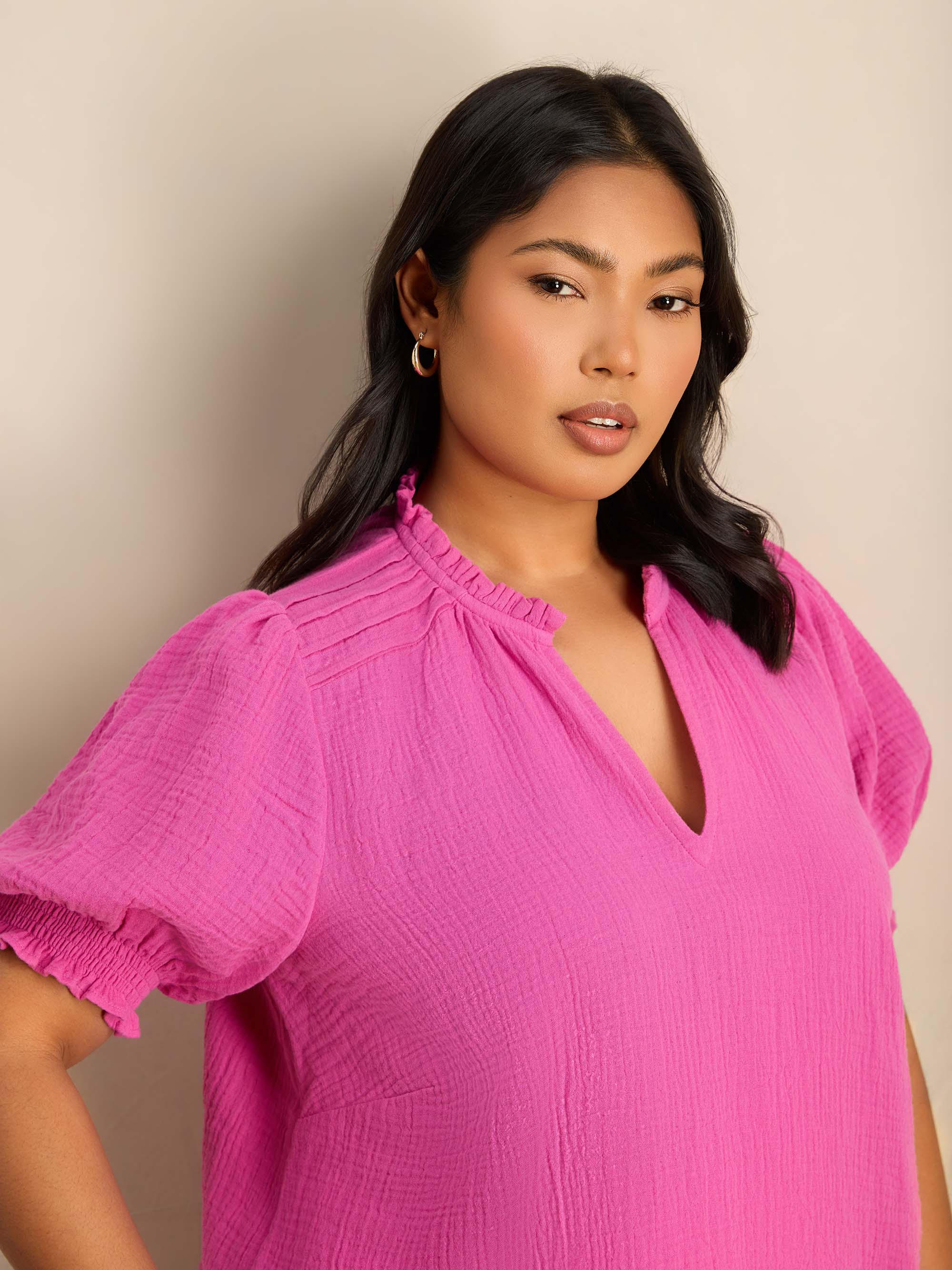 Plus size pink blouse featuring a ruffle collar, pintuck detailing and puff sleeves.