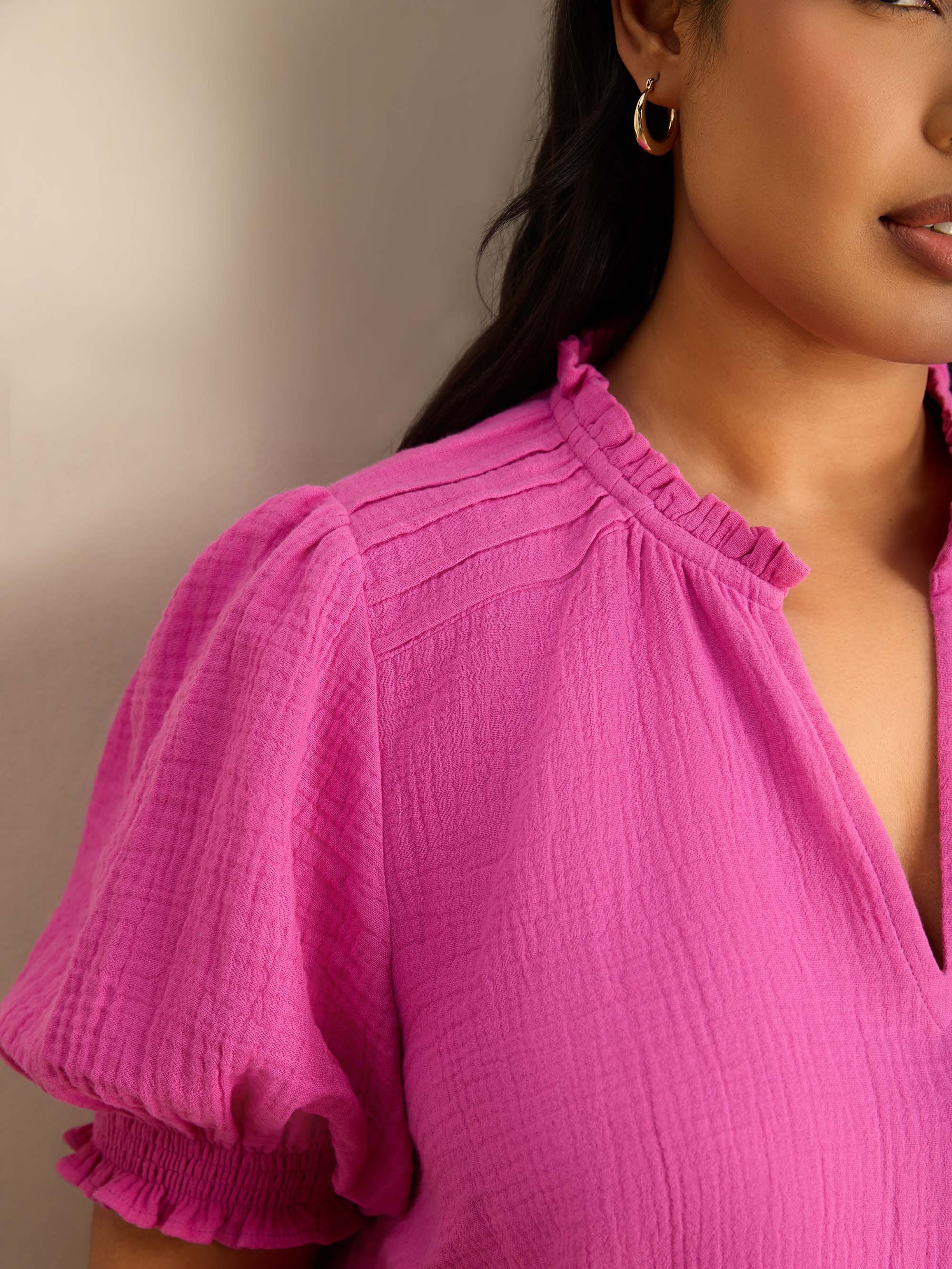 Plus size pink blouse featuring a ruffle collar, pintuck detailing and puff sleeves.