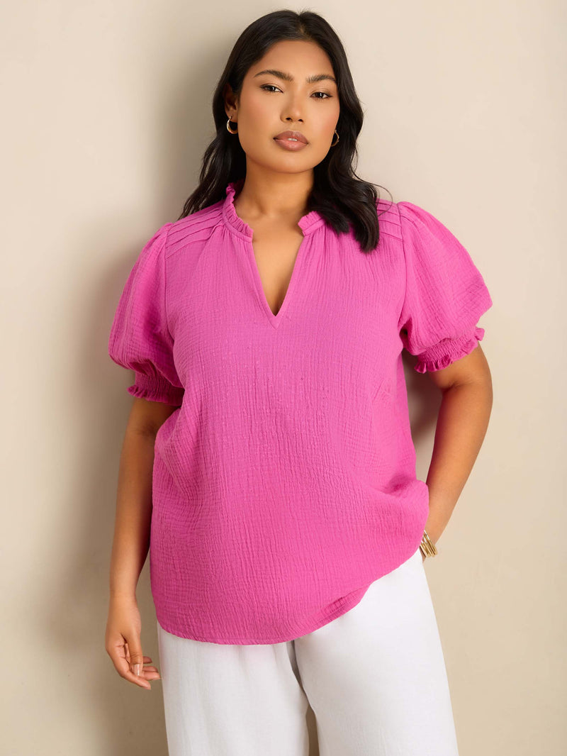 Plus size pink blouse featuring a ruffle collar, pintuck detailing and puff sleeves.
