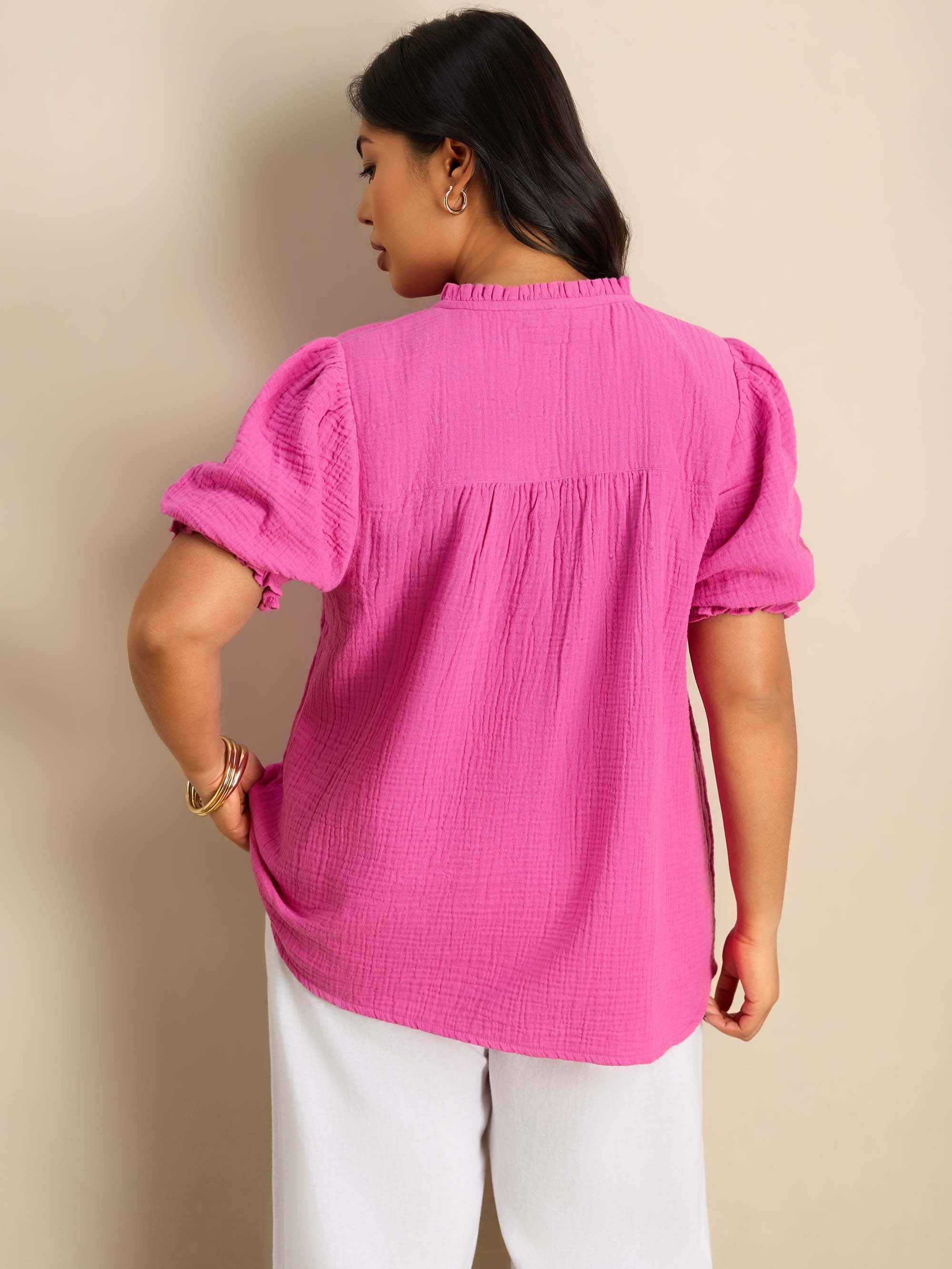 Plus size pink blouse featuring a ruffle collar, pintuck detailing and puff sleeves.