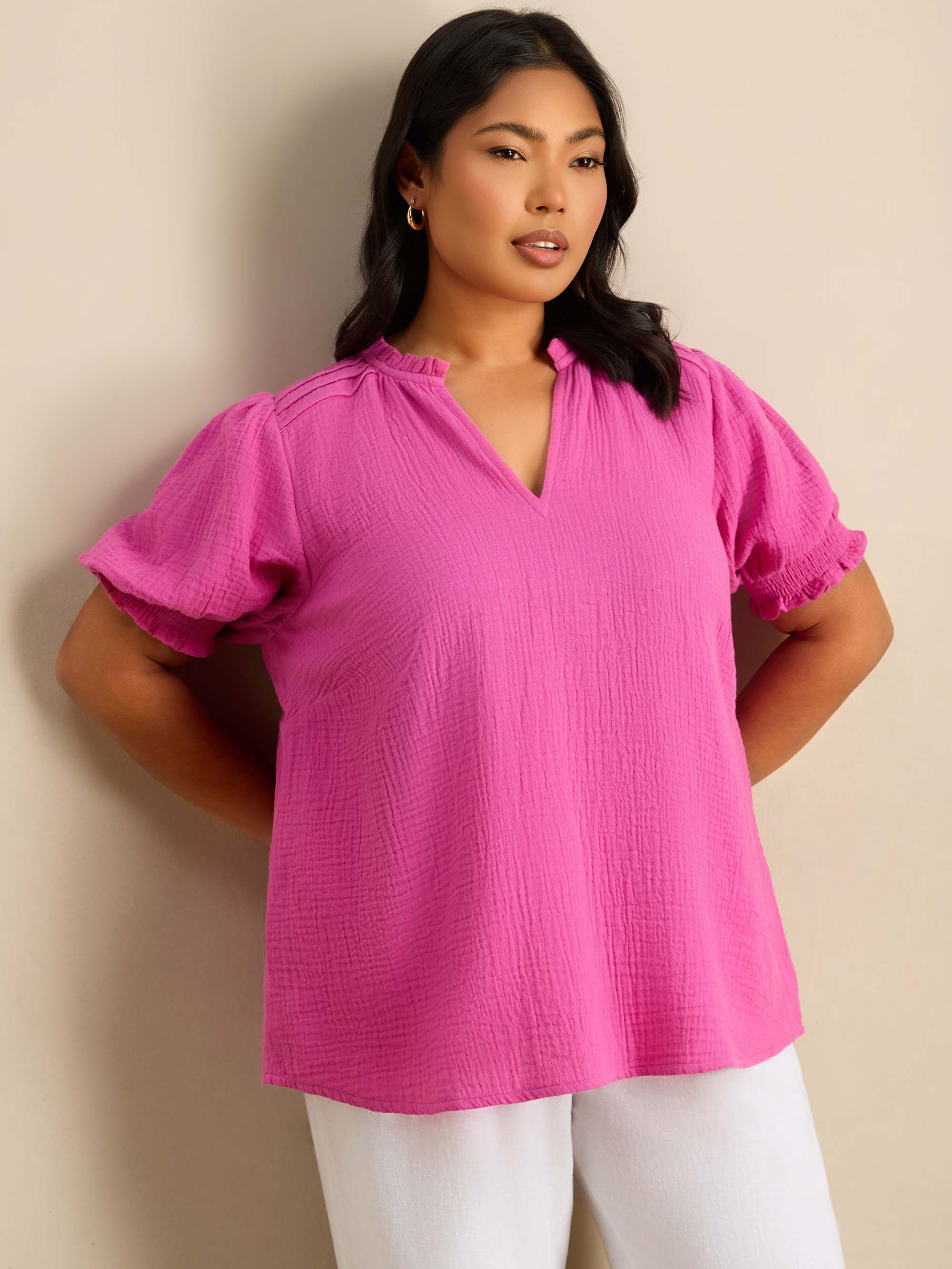 Plus size pink blouse featuring a ruffle collar, pintuck detailing and puff sleeves.
