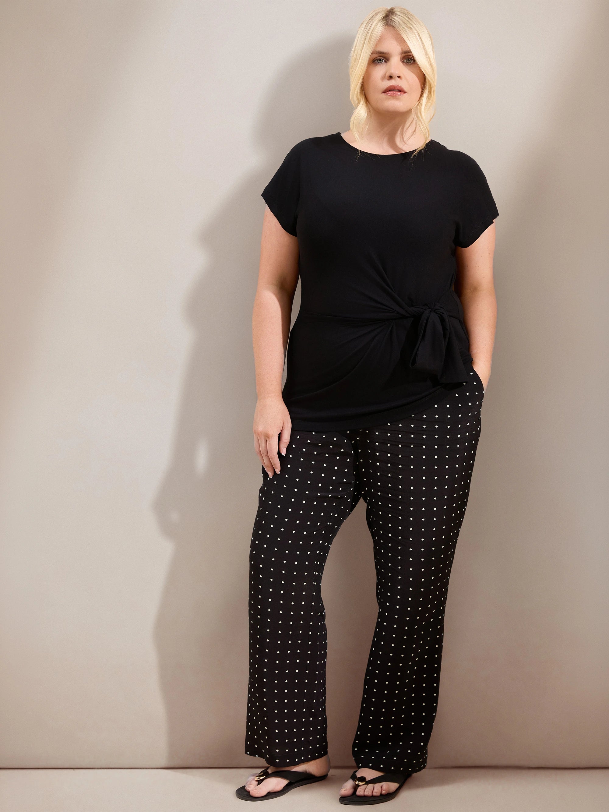 Plus size black jersey top with contrast neckline, cap sleeves and side tie detail, ideal for casual and smart-casual outfits.